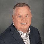 Professional man in business attire smiling for corporate headshot.