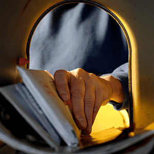 Different types of printed mail being inserted into a mailbox for direct marketing campaigns.