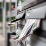 Faded image of a mailbox with direct mail letters and postcards inserted for direct marketing campaigns.