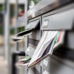 Faded image of a mailbox with direct mail letters and postcards inserted for direct marketing campaigns.