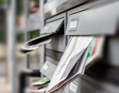 Faded image of a mailbox with direct mail letters and postcards inserted for direct marketing campaigns.