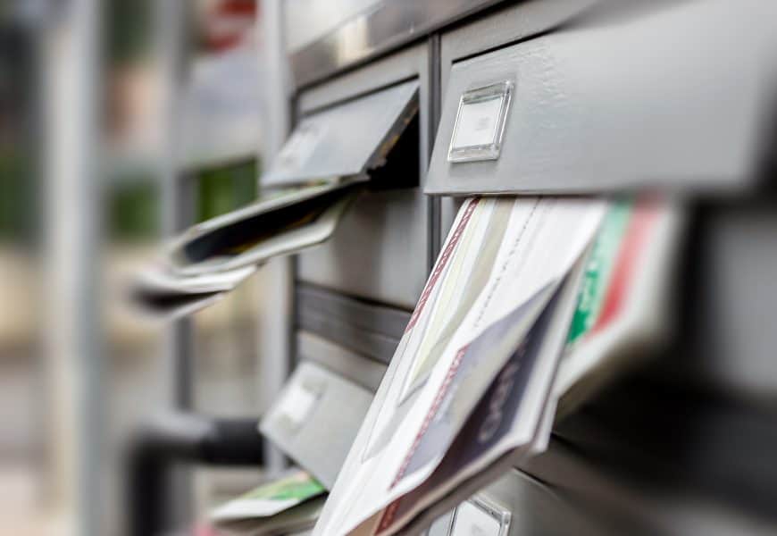 Faded image of a mailbox with direct mail letters and postcards inserted for direct marketing campaigns.