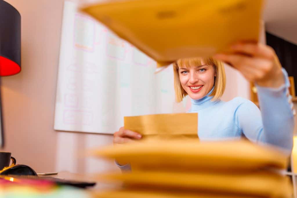 Visually engaging woman opening yellow mailer, direct mail marketing campaign, customer engagement.