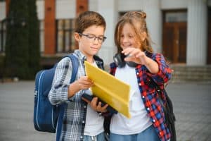 Bright young students with backpacks looking at a tablet outside, promoting effective direct mail marketing strategies.